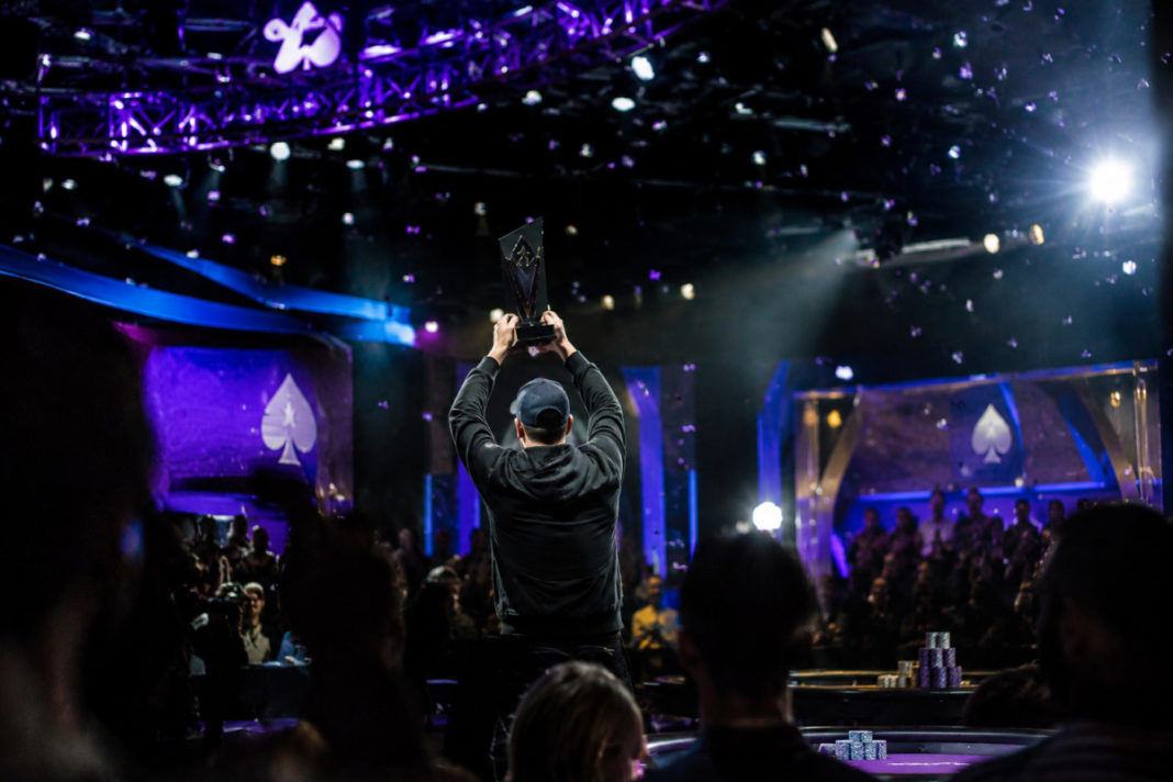 Justin Vaysman brandit le trophée du Poker Masters, jetons sur table.